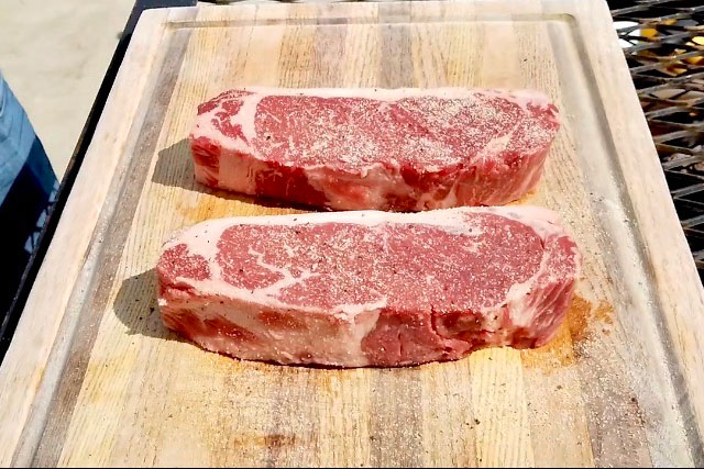 Large Prime New York Strip from Chorizo De San Manuel on wooden cutting board.