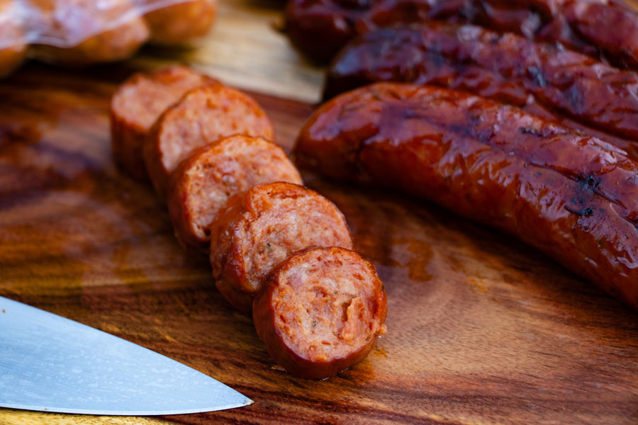 Layers of sausage and Mexican chorizo on a wooden chopping board.