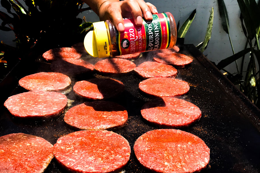 A person cooking prime beef products round patties