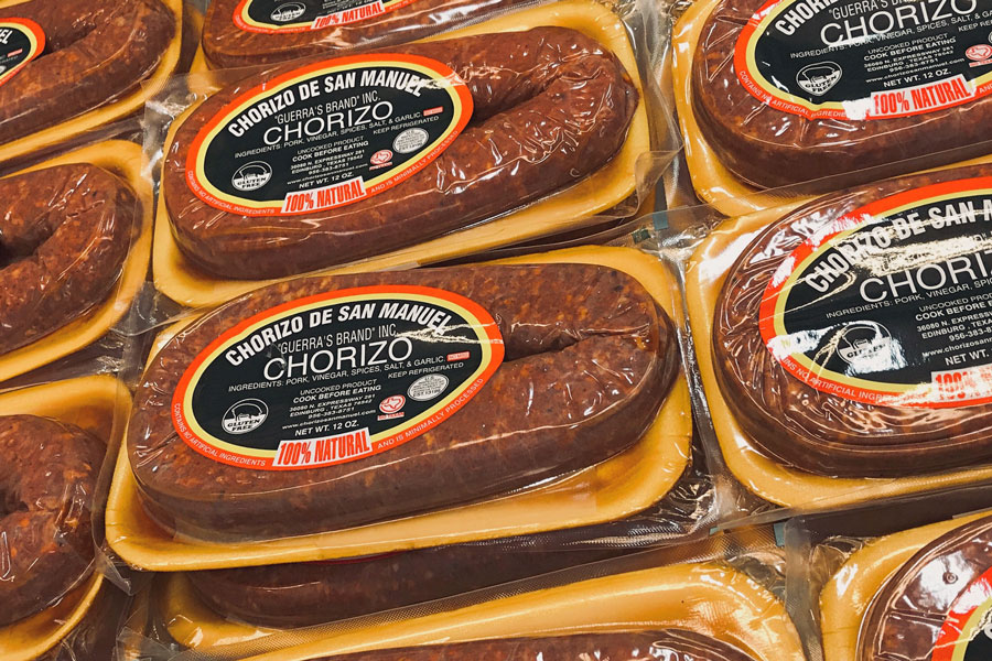 Packages of Mexican brand chorizo stacked on top of one another at a grocery store.