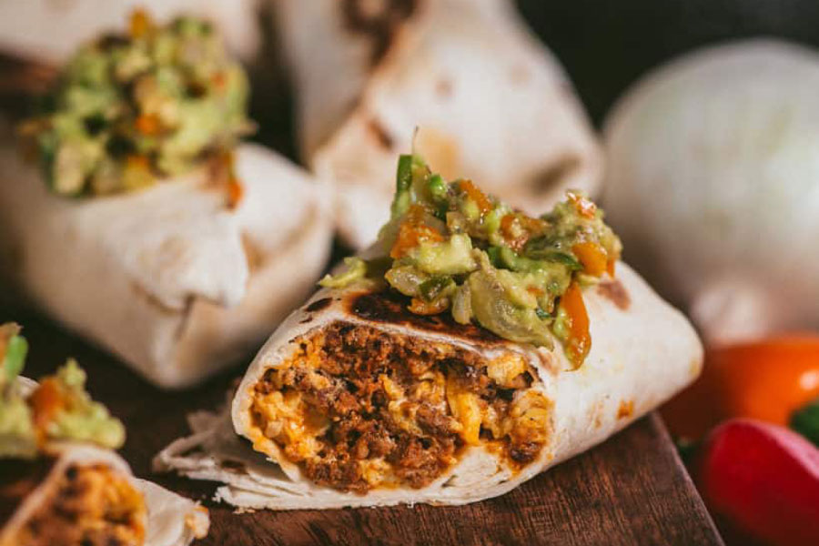 avocado layed on top of a egg burrito stuffed with mexican chorizo brands