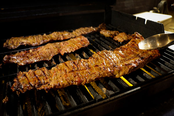 large skirt of beef fajitas and mexican chorizo cooking on a grill