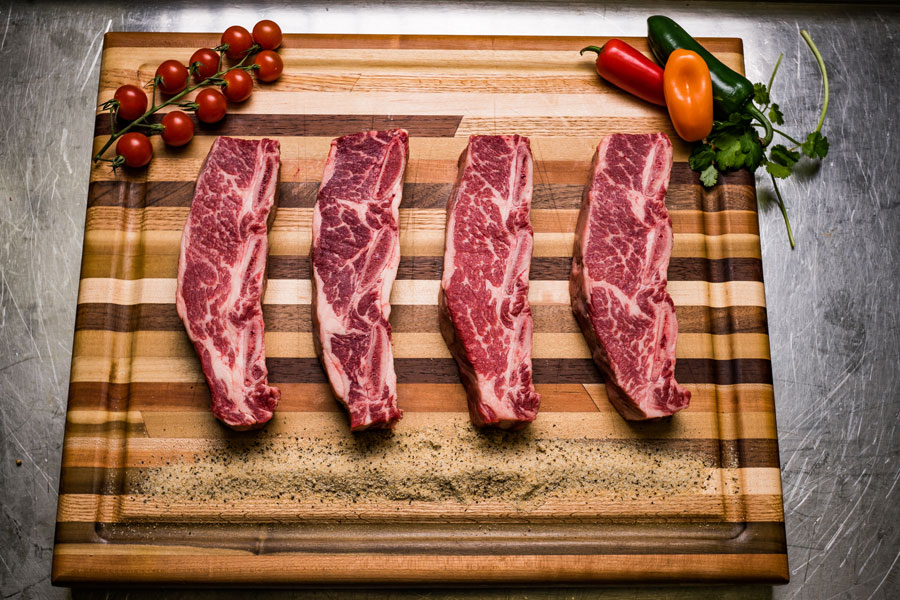 prime rib beef products on a wooden skillet.