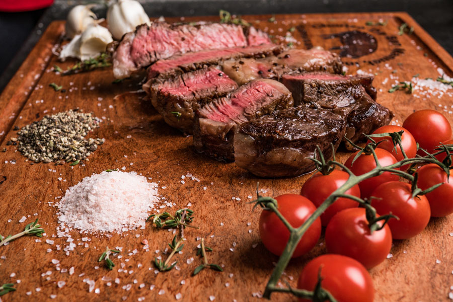 choice vs. prime ribeye steak on wooden board.